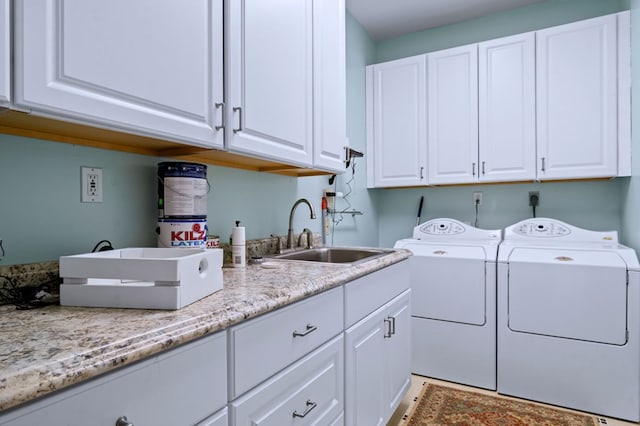 clothes washing area with washer and clothes dryer, a sink, and cabinet space