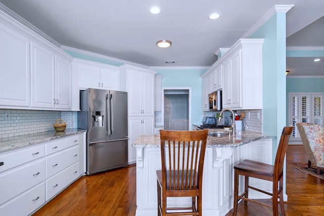 kitchen featuring appliances with stainless steel finishes, a sink, a breakfast bar, and white cabinetry