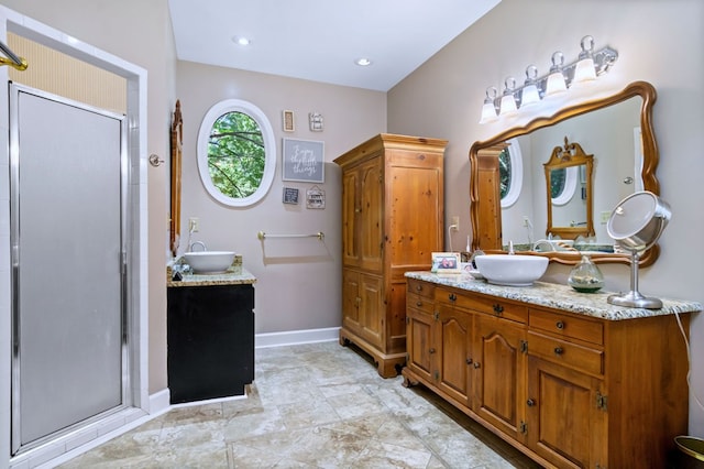 bathroom with a stall shower, two vanities, and a sink