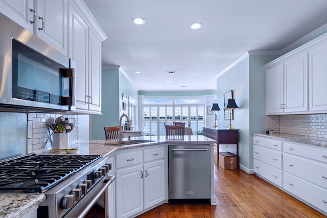 kitchen featuring stainless steel appliances, white cabinets, a sink, and a peninsula