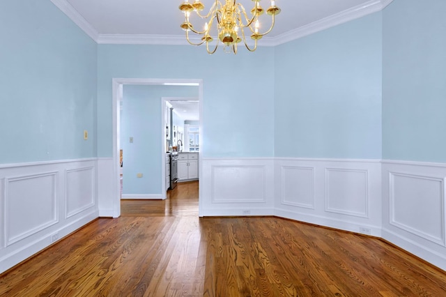 unfurnished dining area featuring ornamental molding, dark wood-style flooring, wainscoting, and a notable chandelier