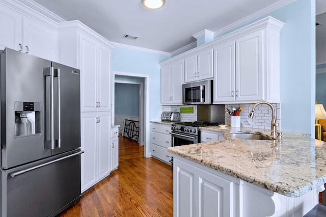 kitchen with a sink, visible vents, white cabinets, appliances with stainless steel finishes, and light stone countertops