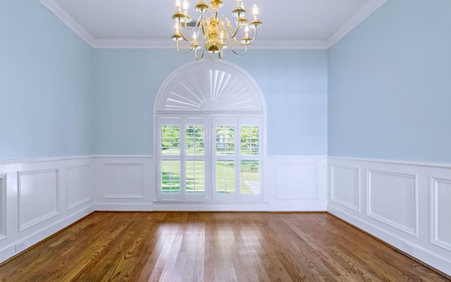 unfurnished room featuring a chandelier, ornamental molding, a wainscoted wall, and wood finished floors