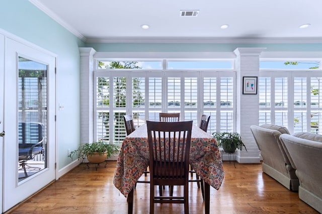 dining room featuring visible vents, crown molding, baseboards, and wood finished floors