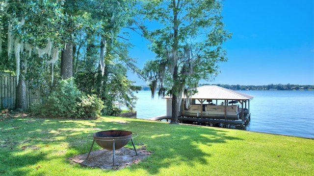 dock area with a water view, a lawn, and a fire pit