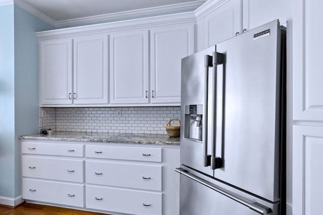 kitchen featuring ornamental molding, high end refrigerator, backsplash, and white cabinetry