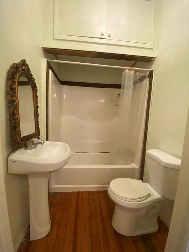 bathroom with hardwood / wood-style flooring, shower / bath combination with curtain, and toilet