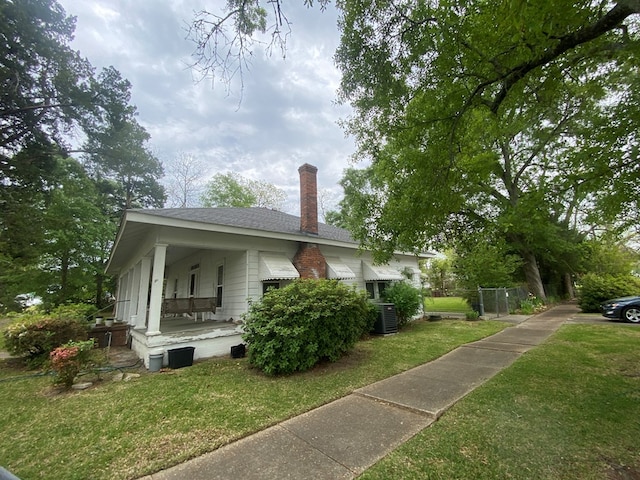 view of property exterior with cooling unit, a yard, and covered porch