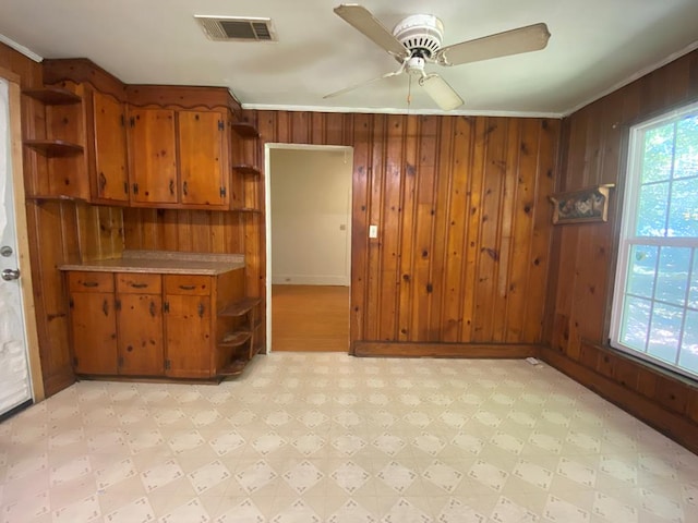 interior space featuring crown molding, ceiling fan, and wooden walls