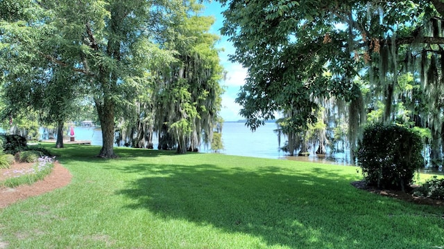 view of home's community with a water view and a yard