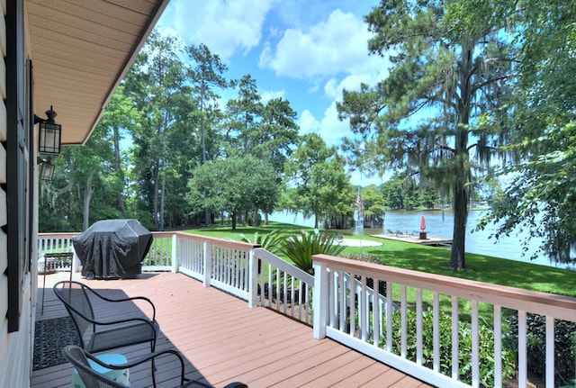 wooden deck with a water view, a lawn, and area for grilling