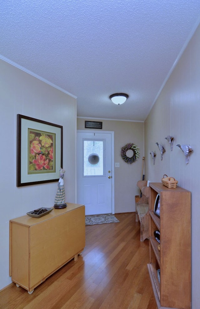 foyer featuring light hardwood / wood-style floors, a textured ceiling, and ornamental molding