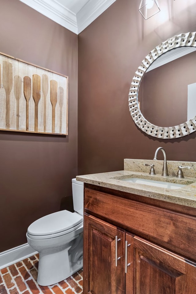 bathroom with baseboards, toilet, ornamental molding, brick floor, and vanity