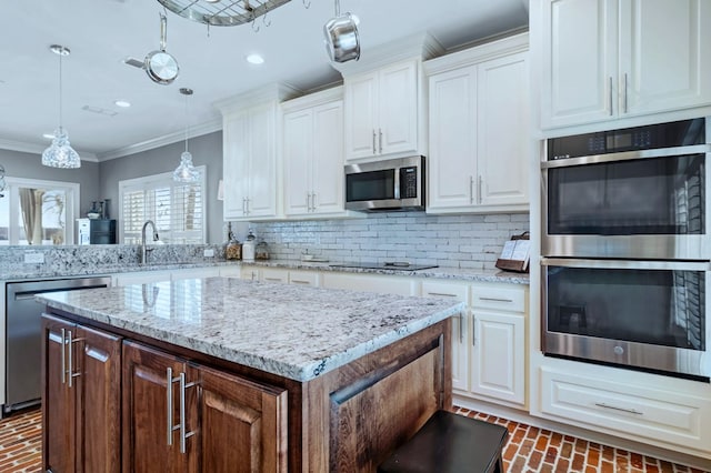 kitchen featuring pendant lighting, stainless steel appliances, brick floor, and white cabinets