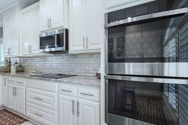 kitchen featuring white cabinets, light stone countertops, stainless steel appliances, and backsplash