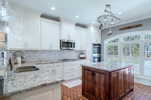 kitchen with appliances with stainless steel finishes, light stone counters, a center island, white cabinetry, and a sink