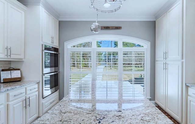 kitchen featuring crown molding, double oven, plenty of natural light, and white cabinets