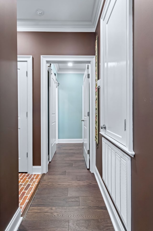 hallway featuring ornamental molding, dark wood-style flooring, and baseboards