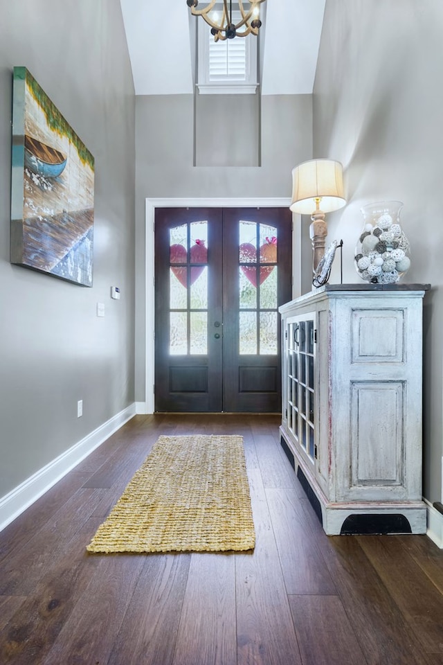 foyer entrance with dark wood-style flooring, french doors, a notable chandelier, high vaulted ceiling, and baseboards