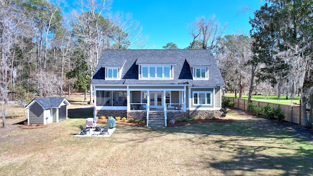 rear view of house featuring a storage unit, an outdoor fire pit, a sunroom, a fenced backyard, and an outdoor structure