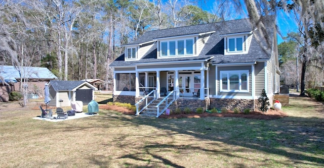 rear view of house featuring a storage shed, a sunroom, a lawn, and an outbuilding