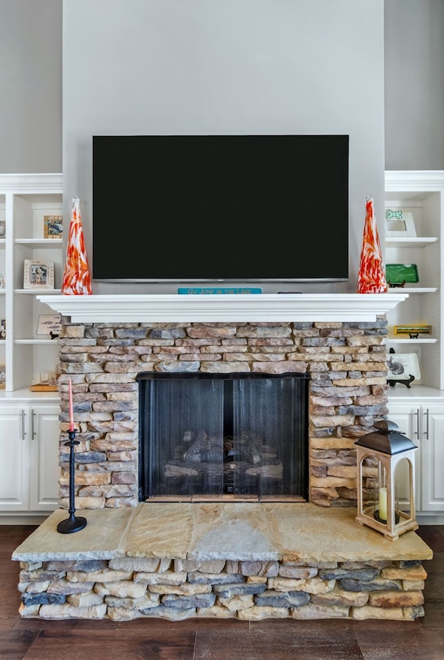 room details featuring built in shelves, a fireplace, and wood finished floors