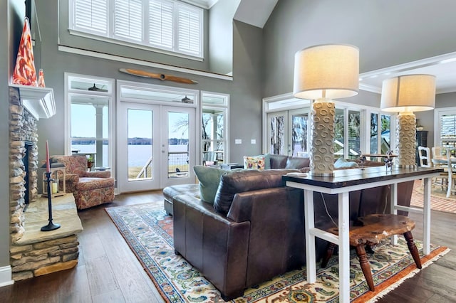 living room featuring a water view, crown molding, dark wood-style flooring, and french doors