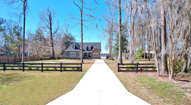 exterior space with concrete driveway, fence, and a front lawn