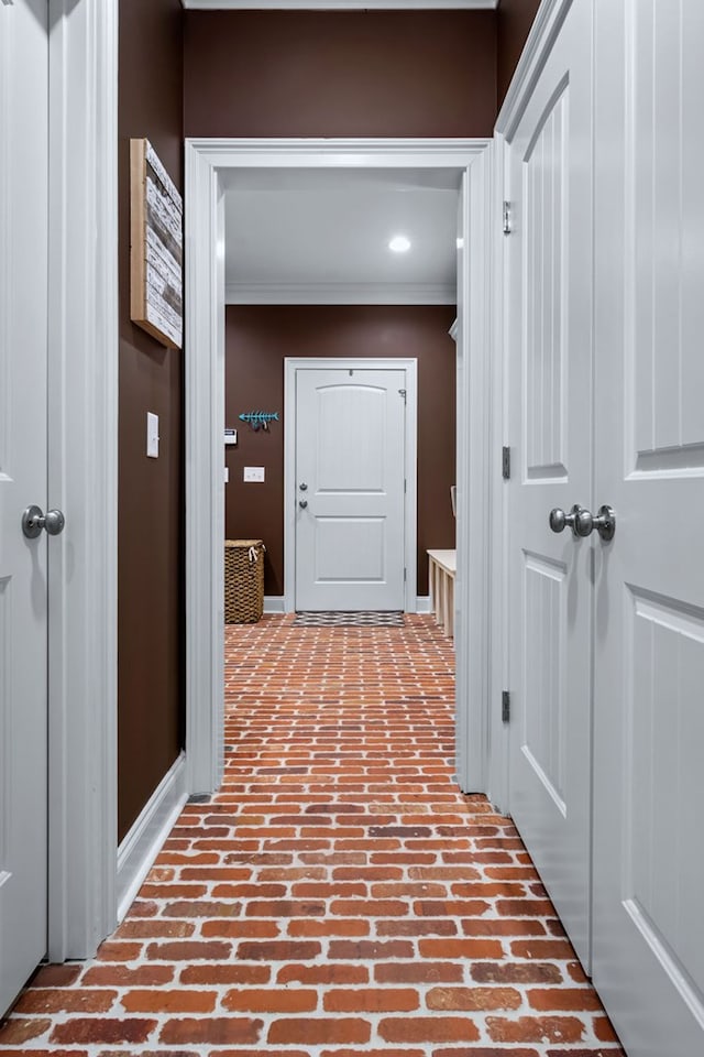 corridor with brick floor and crown molding