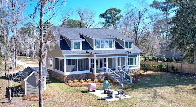 back of house with a fenced backyard, a fire pit, a sunroom, a lawn, and a patio area