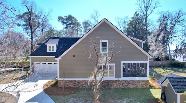 exterior space with driveway, a sunroom, a lawn, and roof with shingles