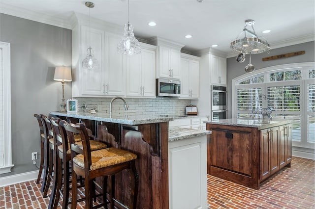 kitchen with light stone counters, stainless steel appliances, a peninsula, white cabinetry, and hanging light fixtures