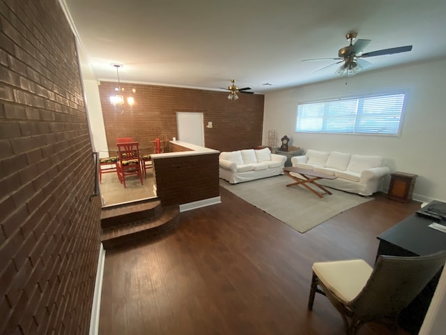 living room with ceiling fan with notable chandelier, brick wall, and dark hardwood / wood-style floors