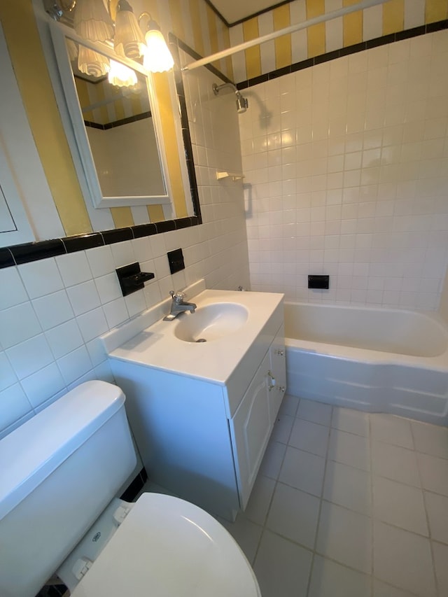 full bathroom with tiled shower / bath, tile patterned floors, vanity, tile walls, and toilet