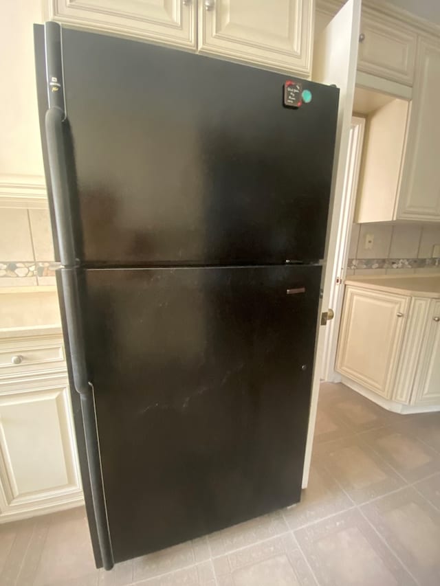 room details featuring cream cabinetry and black fridge