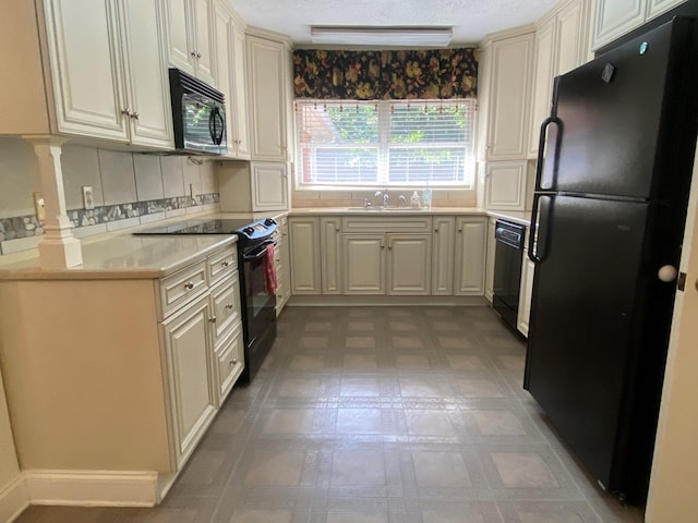 kitchen featuring black appliances, cream cabinets, backsplash, and sink