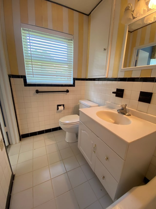 bathroom with tile patterned floors, toilet, tile walls, and vanity