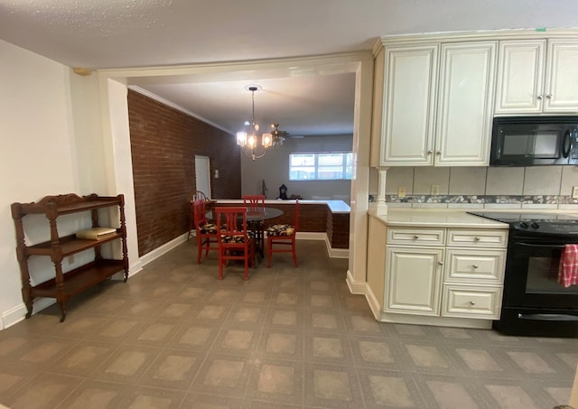 kitchen featuring brick wall, black appliances, decorative light fixtures, cream cabinets, and a notable chandelier