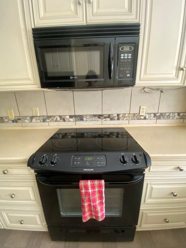 kitchen featuring black appliances and cream cabinetry