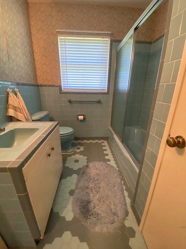 full bathroom with toilet, enclosed tub / shower combo, tile walls, tile patterned flooring, and vanity