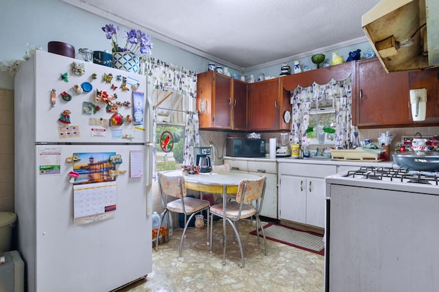 kitchen with ventilation hood, ornamental molding, a textured ceiling, and white appliances