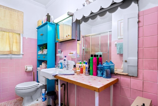 bathroom featuring a shower with door, ornamental molding, tile walls, and toilet