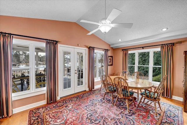 dining space with ceiling fan, a textured ceiling, vaulted ceiling, french doors, and light wood-type flooring