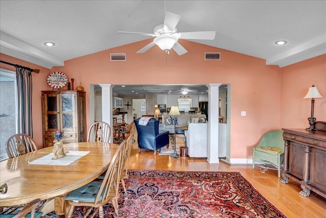 dining room featuring decorative columns, ceiling fan, lofted ceiling, and light wood-type flooring