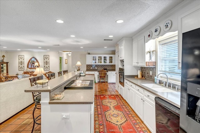 kitchen with sink, white cabinets, a kitchen breakfast bar, and black appliances