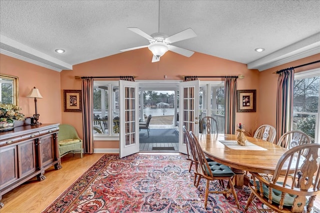 dining space with lofted ceiling, light wood-type flooring, and french doors