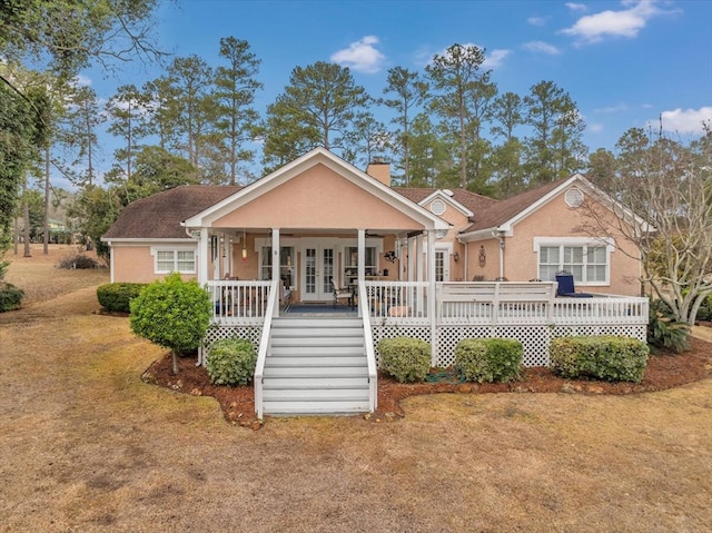 view of front of home with a front yard, french doors, and a porch