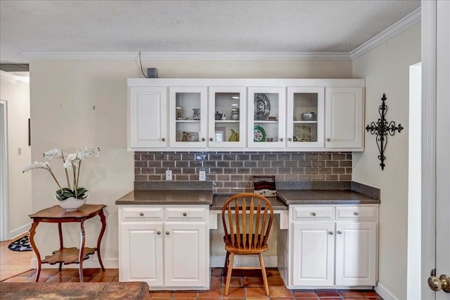 bar featuring ornamental molding, built in desk, and white cabinets