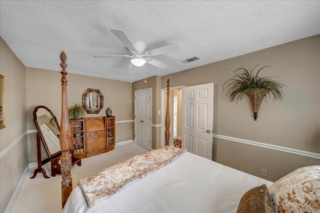 bedroom with ceiling fan, light carpet, and a textured ceiling