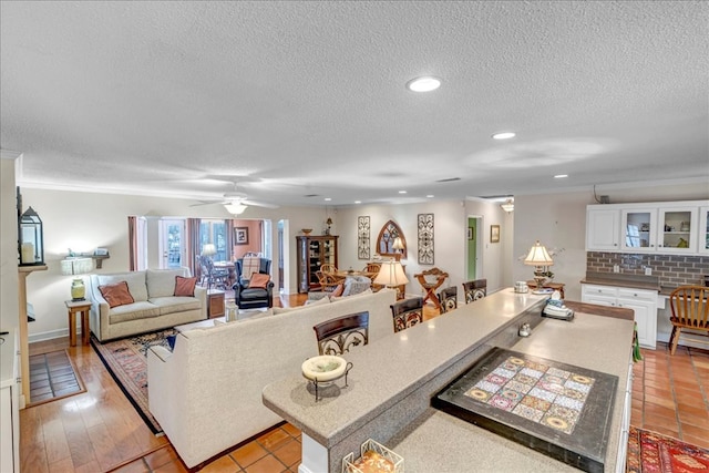 living room with ceiling fan, ornamental molding, and a textured ceiling